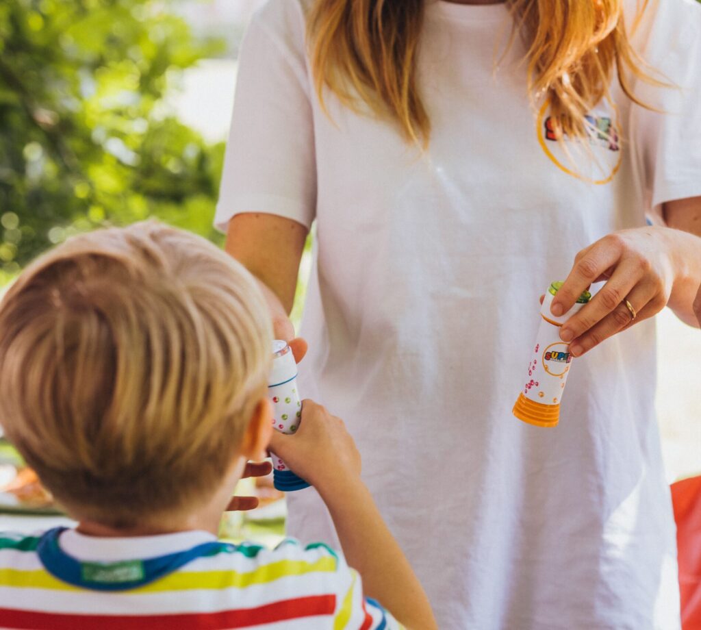 Una animadora entregando un bote de burbujas de jabón a un niño, durante una de nuestras fiestas infantiles personalizadas a domicilio.